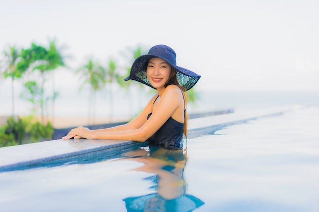 Il sorriso felice delle belle giovani donne asiatiche del ritratto si rilassa la piscina all'aperto in hotel