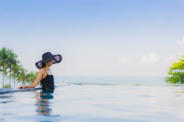 Il sorriso felice delle belle giovani donne asiatiche del ritratto si rilassa la piscina all'aperto in hotel