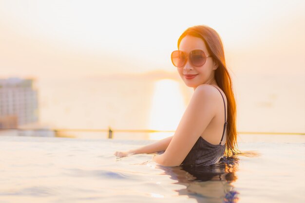 Il sorriso felice delle belle giovani donne asiatiche del ritratto si rilassa la piscina all'aperto in hotel