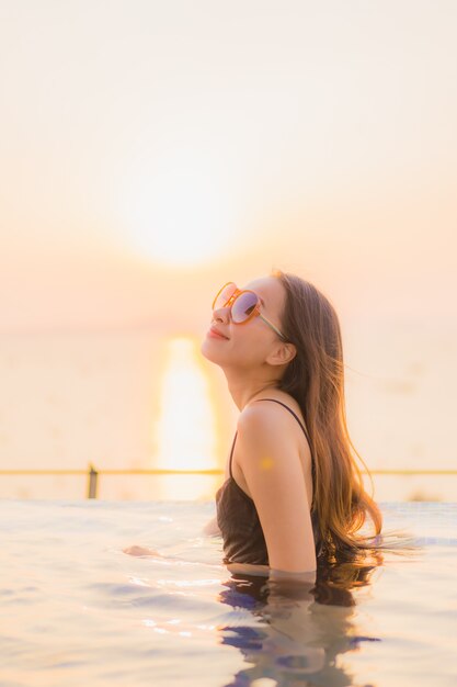 Il sorriso felice delle belle giovani donne asiatiche del ritratto si rilassa la piscina all'aperto in hotel