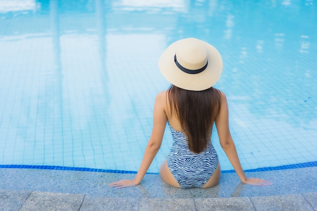 Il sorriso felice delle belle giovani donne asiatiche del ritratto si rilassa la piscina all'aperto nella località di soggiorno