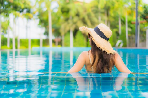 Il sorriso felice delle belle giovani donne asiatiche del ritratto si rilassa la piscina all'aperto nella località di soggiorno