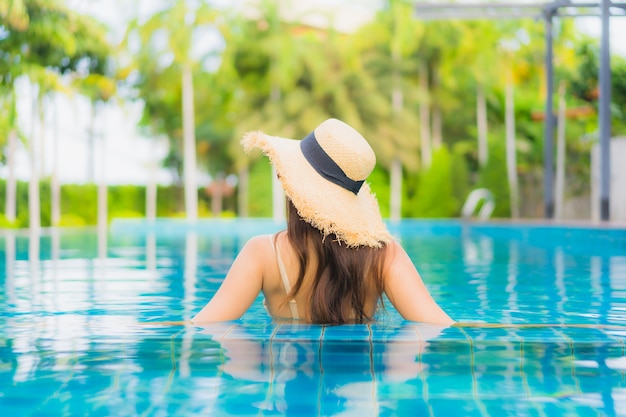 Il sorriso felice delle belle giovani donne asiatiche del ritratto si rilassa la piscina all'aperto nella località di soggiorno