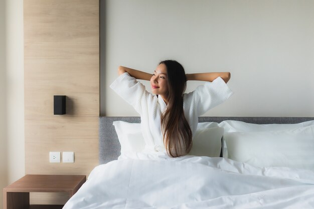 Il sorriso felice delle belle giovani donne asiatiche del ritratto si rilassa sul letto