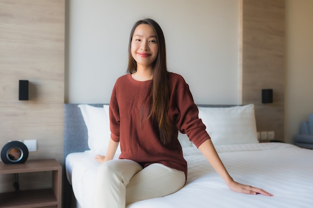Il sorriso felice delle belle giovani donne asiatiche del ritratto si rilassa sul letto