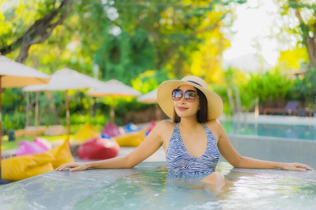 Il sorriso felice delle belle giovani donne asiatiche si rilassa intorno alla piscina all'aperto nella località di soggiorno dell'hotel per il viaggio nella vacanza di festa