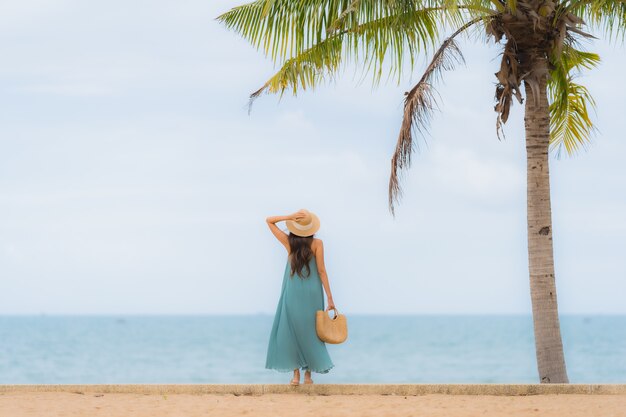 Il sorriso felice delle giovani donne asiatiche del bello ritratto si rilassa intorno all'oceano del mare della spiaggia