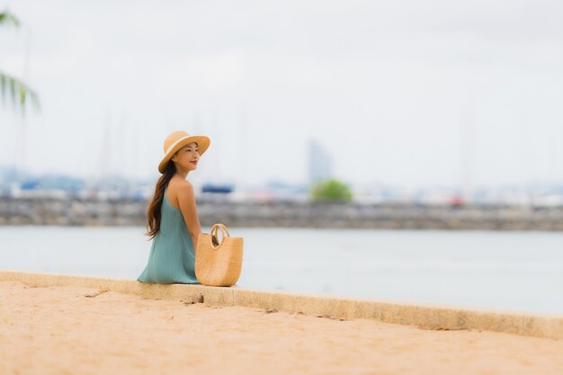 Il sorriso felice delle giovani donne asiatiche del bello ritratto si rilassa intorno all'oceano del mare della spiaggia