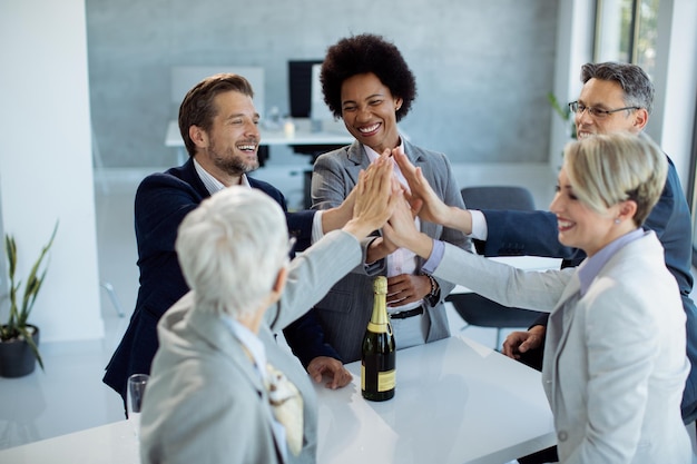 Il successo del team aziendale che raccoglie le mani nell'unità mentre festeggia in ufficio