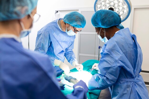 Il team di chirurghi in uniforme esegue un'operazione su un paziente in una clinica di cardiochirurgia Medicina moderna un team di professionisti della salute dei chirurghi