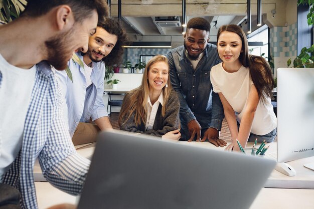 Il team di diversi colleghi in un ufficio moderno discute insieme il loro progetto