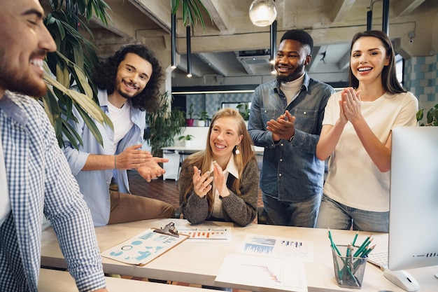 Il team di diversi colleghi in un ufficio moderno discute insieme il loro progetto