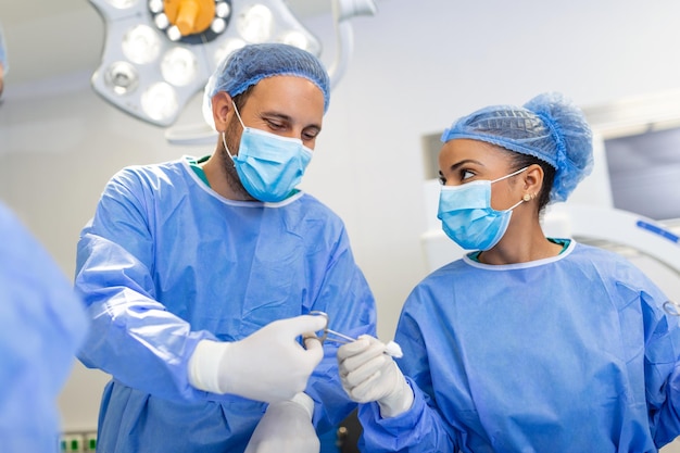 Il team medico e infermieristico sta eseguendo un'operazione chirurgica al pronto soccorso dell'assistente ospedaliero distribuisce forbici e strumenti ai chirurghi durante l'operazione