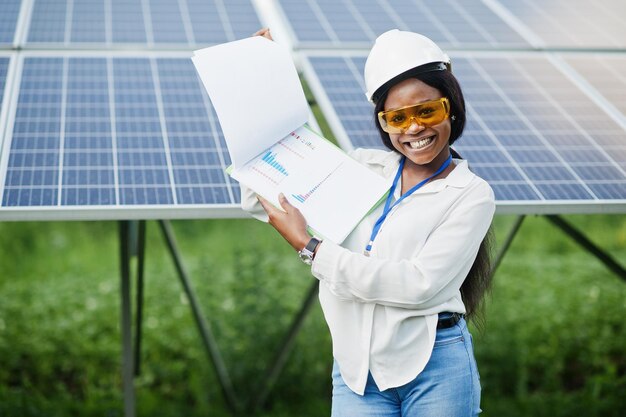 Il tecnico afroamericano controlla la manutenzione dei pannelli solari Ingegnere donna nera alla stazione solare