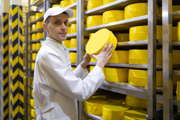 Il tecnologo con il formaggio tra le mani effettua un'ispezione della produzione pronta presso il dipartimento del caseificio