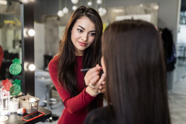 Il truccatore propone di cambiare il colore del rossetto in una giovane modella con i capelli lunghi