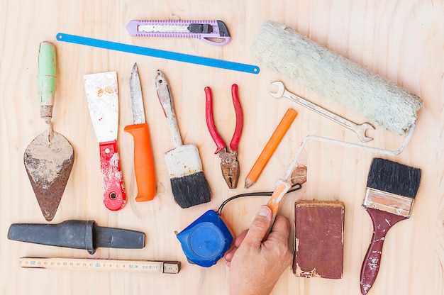 Il vecchio corredo di attrezzi per bricolage della costruzione con l&#39;operaio consegna il fondo di legno bianco