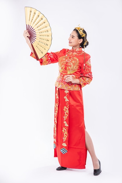 Il vestito da Cheongsam di usura della donna mostra il ventilatore cinese della mano sul grande evento nel nuovo anno cinese