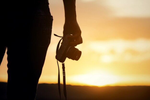 Il viaggiatore con zaino e sacco a pelo si rilassa sulla montagna con la macchina fotografica e il tramonto