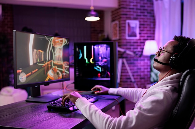 Il vlogger su Internet che trasmette videogiochi dal vivo gioca sul computer, divertendosi con il torneo di campionato di giochi online in streaming. Giocatore virtuale che gioca a una competizione di eSport alla scrivania con luci al neon.