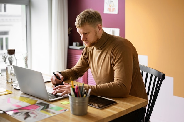 Illustratore maschio adulto che lavora sul dispositivo tablet