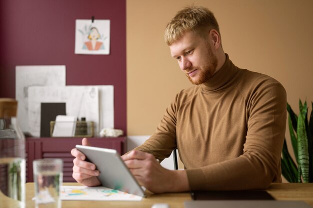 Illustratore maschio adulto che lavora sul dispositivo tablet