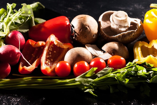 Immagine artistica di diversi tipi di verdure biologiche sane su sfondo scuro in studio fotografico