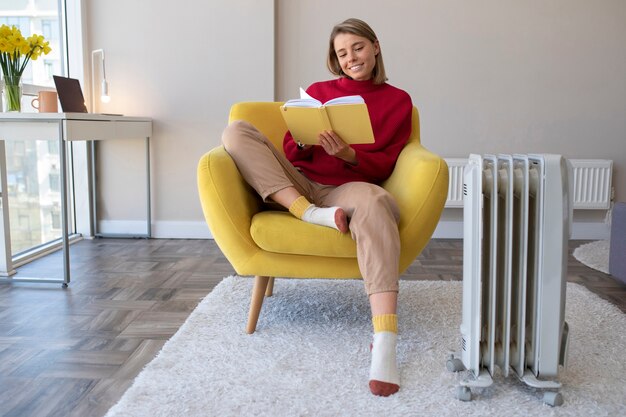 Immagine completa di una donna sorridente che legge a casa