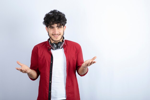 Immagine del giovane ragazzo in cuffie in piedi su sfondo bianco. Foto di alta qualità