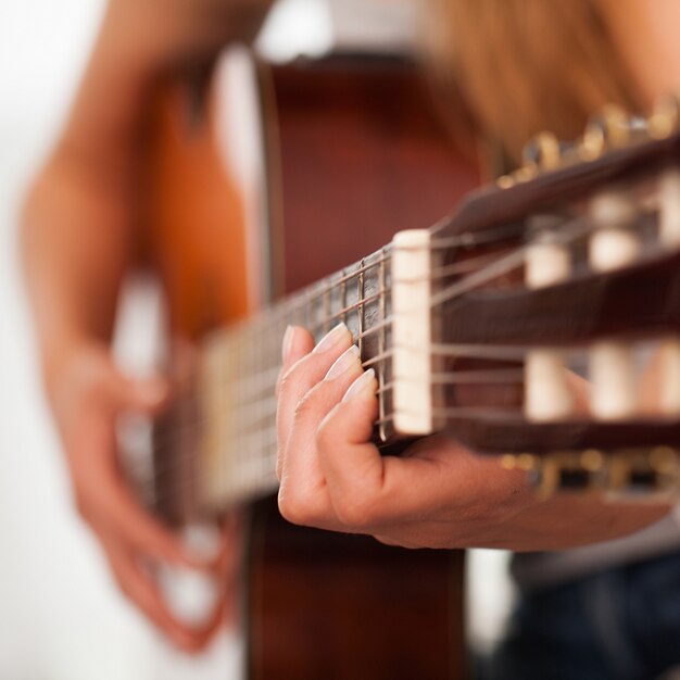 Immagine del primo piano della chitarra in mani della donna