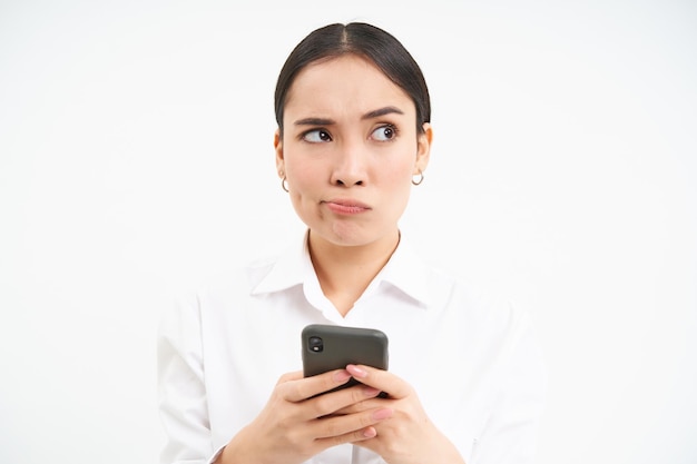 Immagine del responsabile dell'ufficio della commessa asiatica che tiene lo smartphone che lavora al testo per i social media utilizzando c