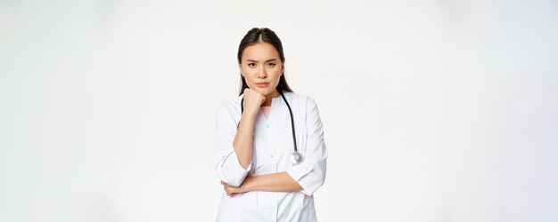 Immagine dell'infermiera asiatica dottoressa arrabbiata che sembra infastidita e infastidita con le sopracciglia solcate e imbronciata premurosa in piedi su sfondo bianco
