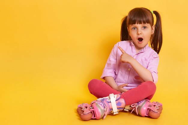 Immagine della bambina stupita con la bocca ampiamente aperta che si siede sul pavimento