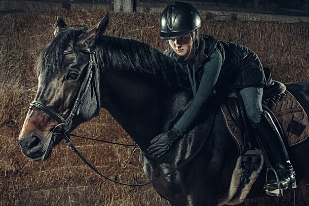 Immagine della femmina felice che si siede sul cavallo di razza