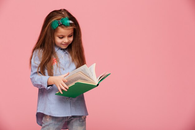 Immagine della studentessa intelligente con lunghi capelli ramati che legge libro interessante