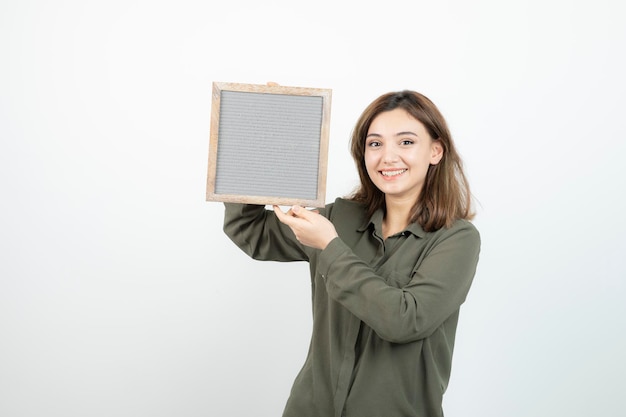 Immagine di adorabile giovane donna che tiene cornice vuota su bianco. Foto di alta qualità