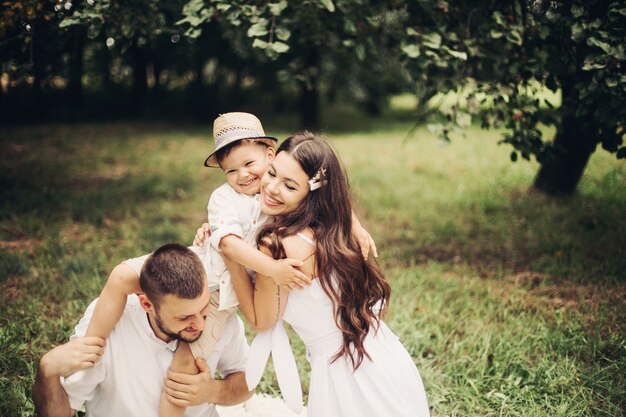 Immagine di allegra mamma caucasica, papà e il loro bambino si divertono insieme e sorridono in giardino