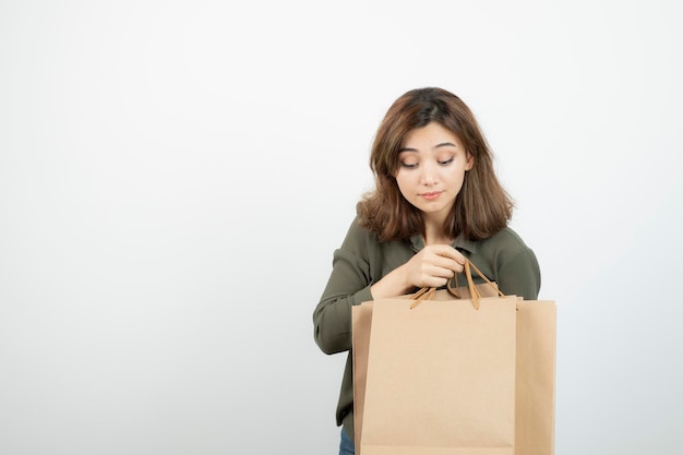 Immagine di bella donna che toglie qualcosa dalla borsa artigianale. Foto di alta qualità