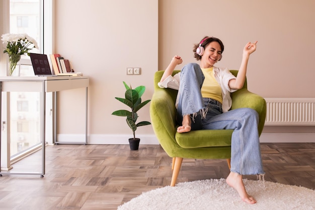 Immagine di bella donna seduta a casa e ascoltando musica