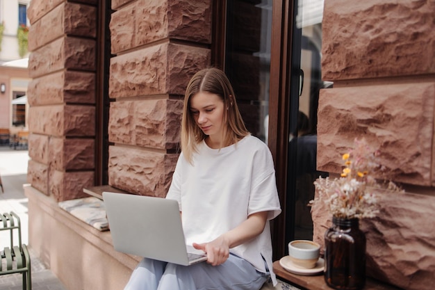 Immagine di donna allegra seduta con laptop e caffè