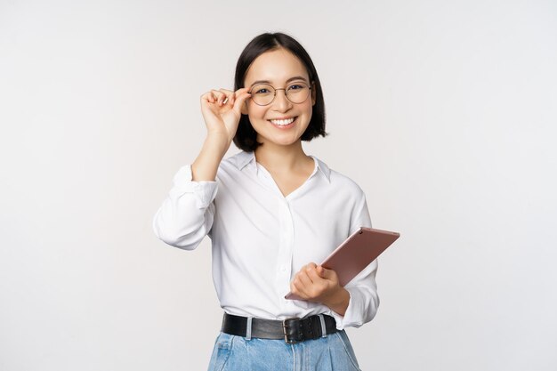 Immagine di giovane donna d'affari asiatica imprenditrice in bicchieri tenendo tablet e cercando professionale in bicchieri sfondo bianco