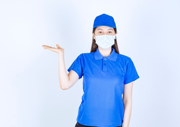 Immagine di giovane donna in uniforme che indossa maschera medica e posa.