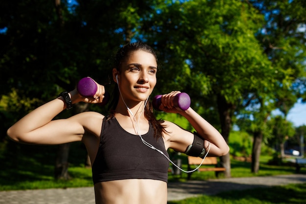 Immagine di giovane ragazza attraente di forma fisica che tiene i dumbbells