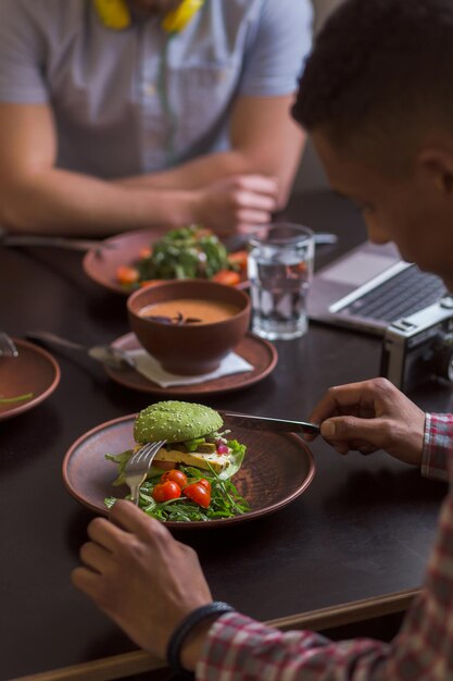 Immagine di persone sedute in un bar o ristorante vegano e che mangiano un gustoso panino vegetariano