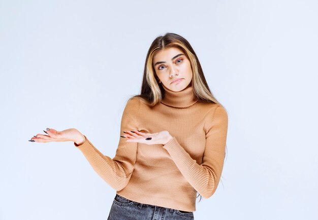 Immagine di un modello di giovane donna in maglione marrone in piedi e in posa.
