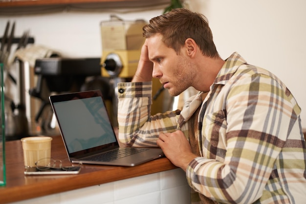 Immagine di un uomo adulto che sembra complicato sullo schermo del portatile che fissa perplesso il suo monitor che fa