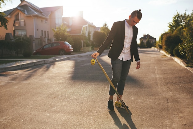 Immagine di un uomo con longboard andando sulla strada