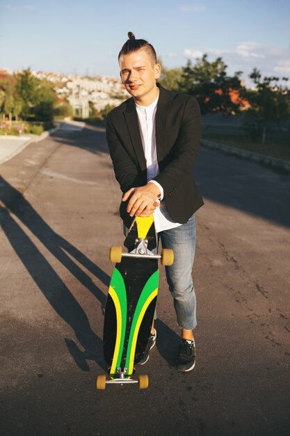 Immagine di un uomo con longboard andando sulla strada