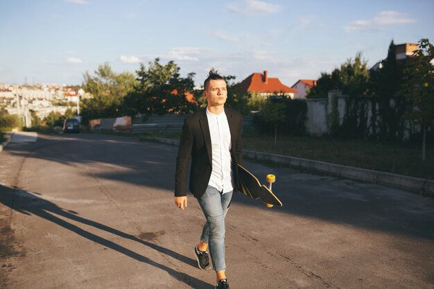 Immagine di un uomo con longboard andando sulla strada