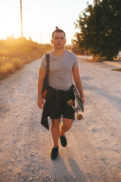 Immagine di un uomo con longboard andando sulla strada